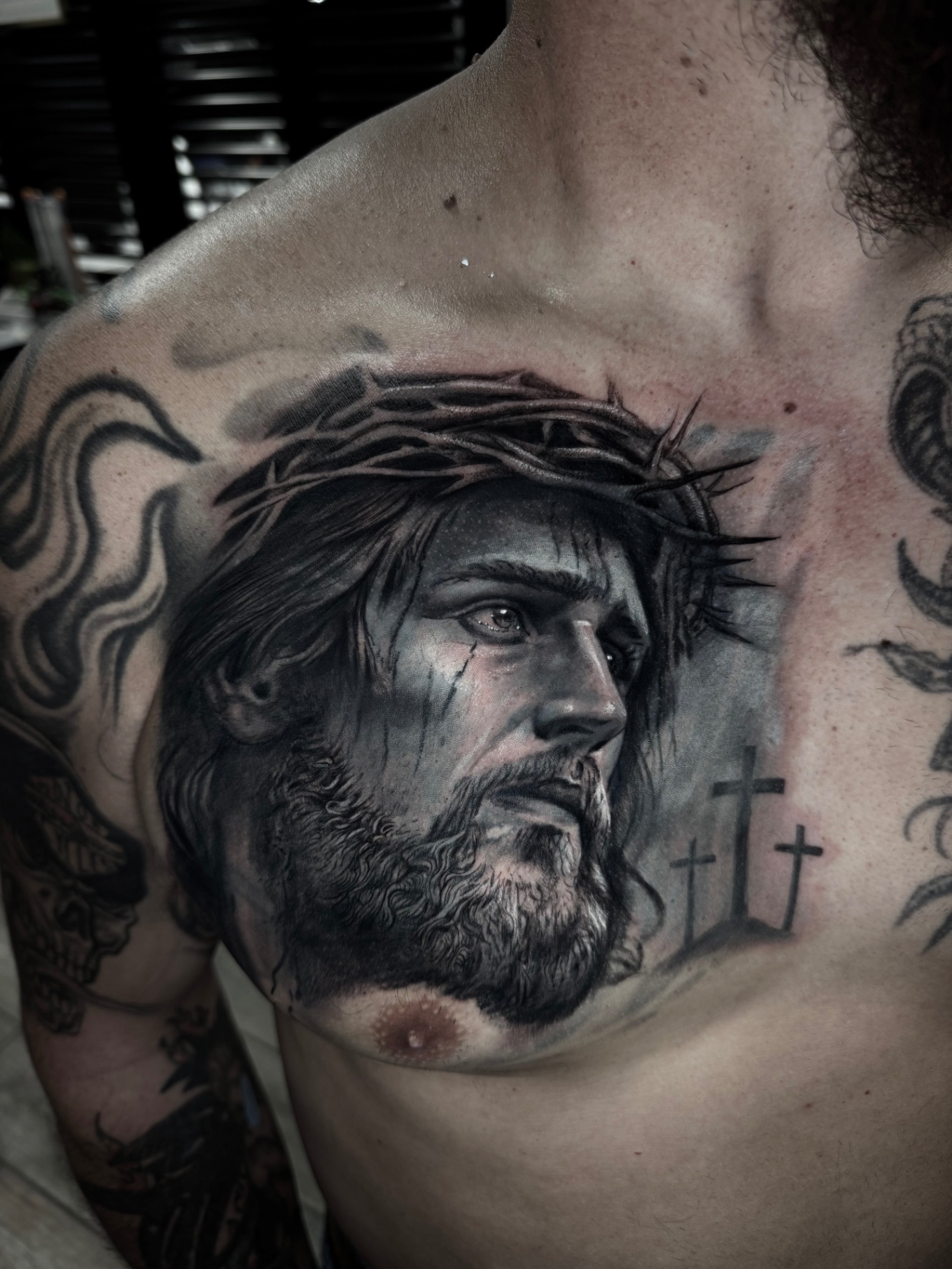 Black and grey portrait tattoo of Christ with crown of thorns on the chest