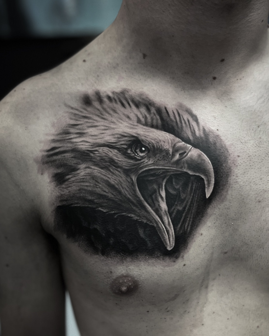 Black and grey eagle head tattoo across the chest